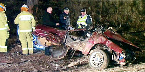 Emergency service workers inspect the car wreck in which four people died on Saturday. Emergency service workers inspect the car wreck in which four people died on Saturday.